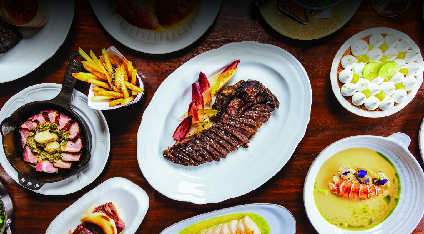 A beautifully plated steak accompanied by a variety of colorful vegetables on a pristine white plate.