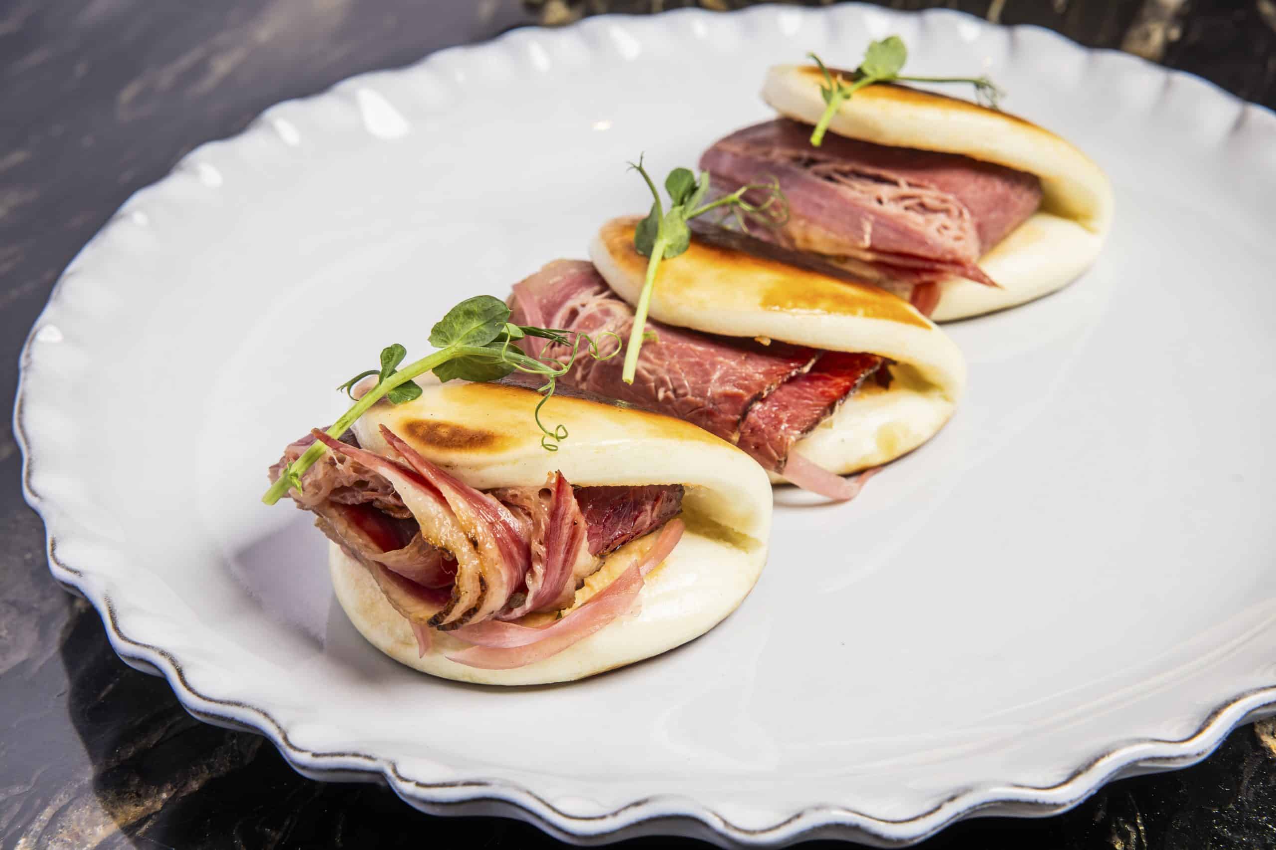 Three small sandwiches arranged neatly on a white plate.