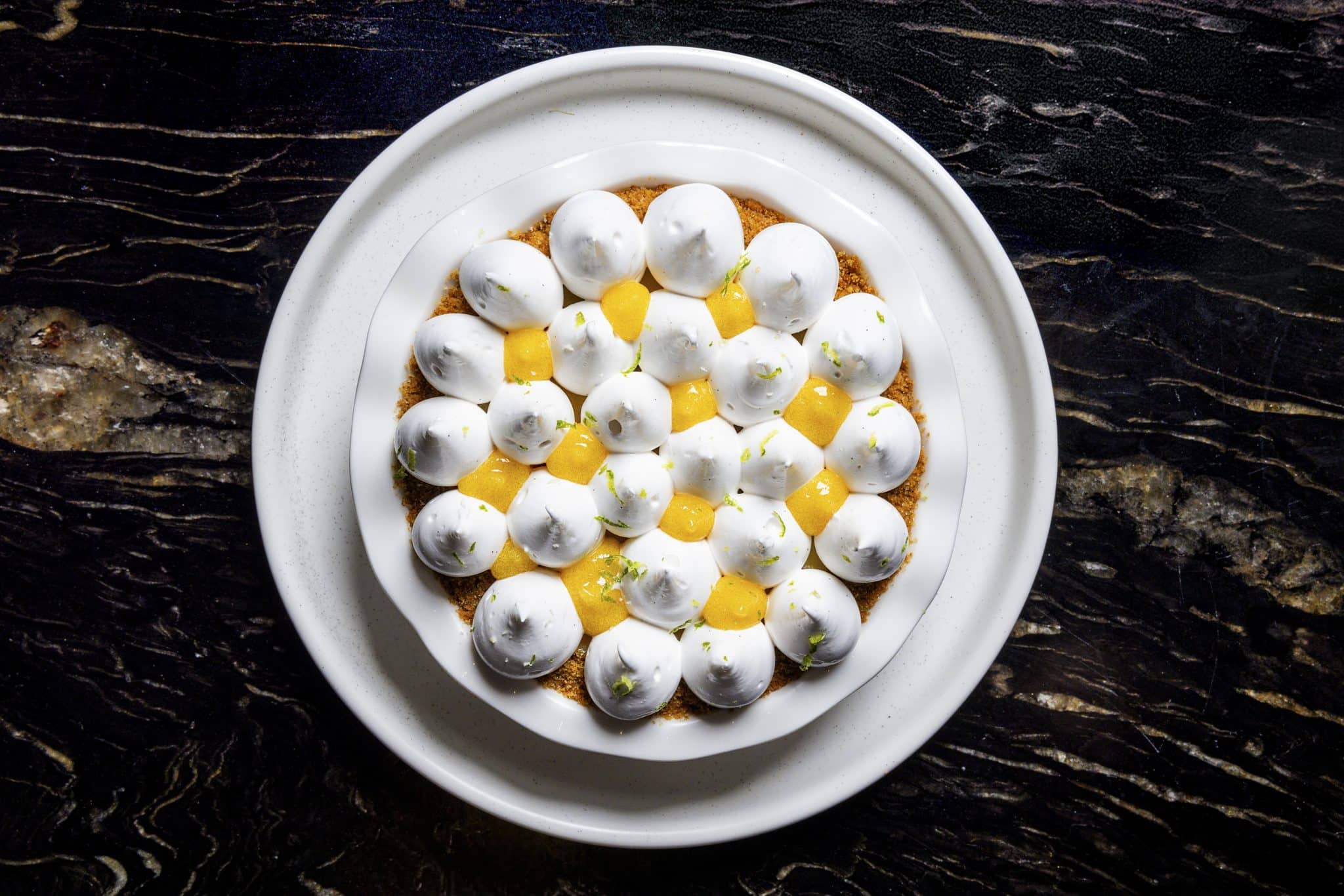 A white plate featuring a serving of eggs garnished with a slice of lemon.